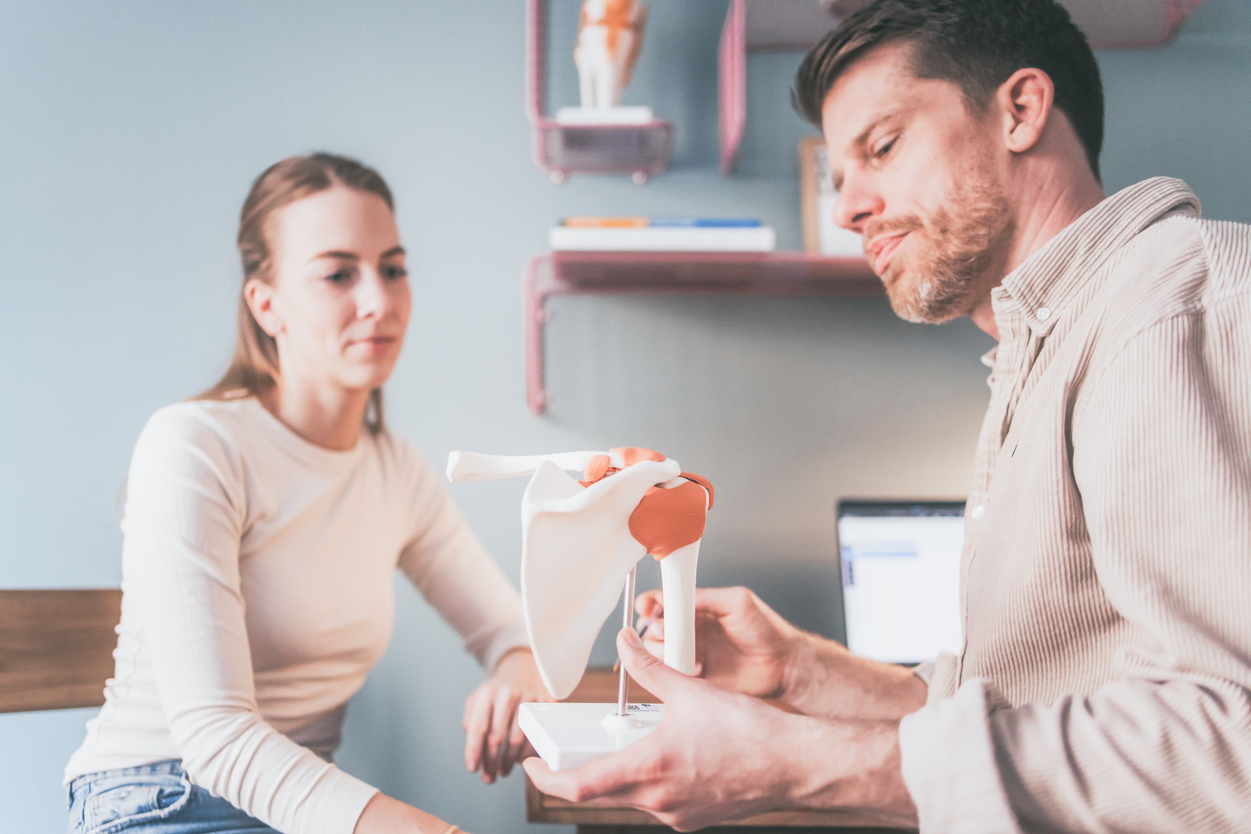 Daniel zeigt einer Patientin Modell von Schultergelenk